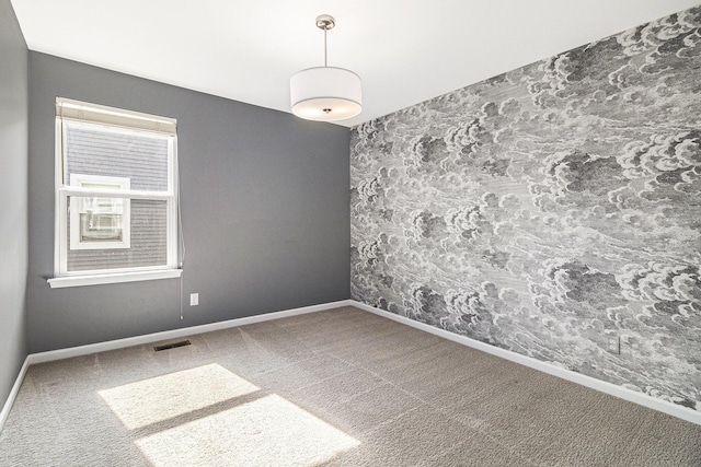 spare room featuring carpet, visible vents, and baseboards