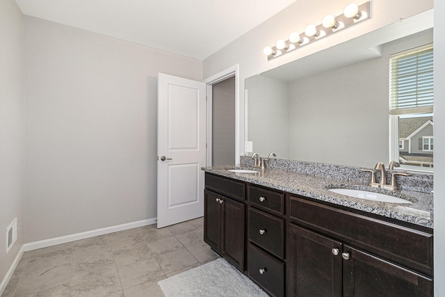 bathroom featuring double vanity, baseboards, and a sink