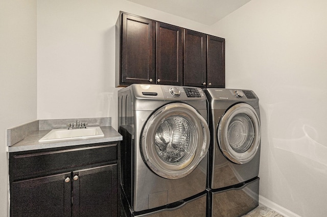 laundry room featuring cabinet space, baseboards, washer and dryer, and a sink