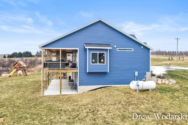 rear view of house with a patio area, a playground, and a lawn