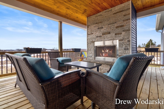 wooden deck with an outdoor stone fireplace