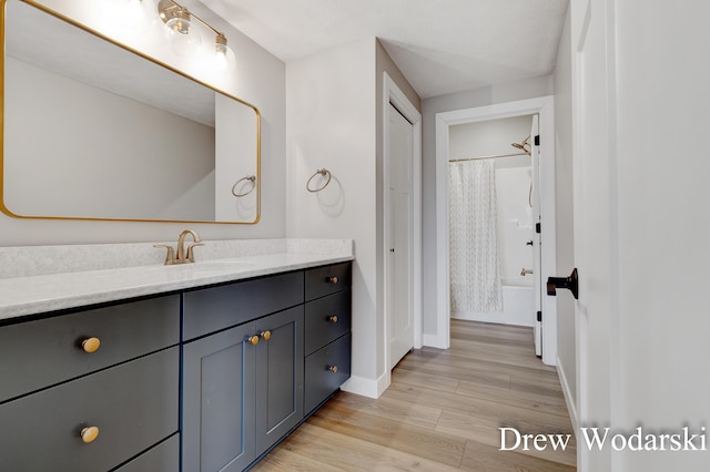 full bath featuring vanity, baseboards, and wood finished floors