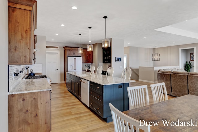 kitchen featuring light wood-style flooring, backsplash, open floor plan, a sink, and white appliances