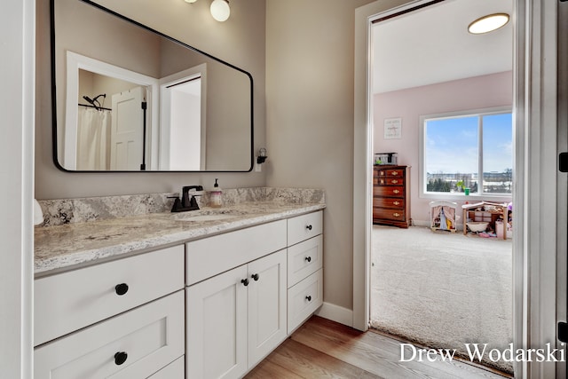 bathroom featuring baseboards, wood finished floors, and vanity