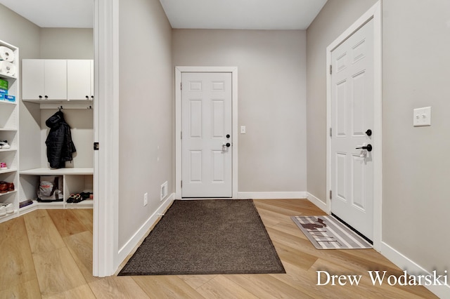 entryway with baseboards, visible vents, and light wood finished floors