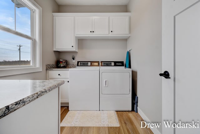 laundry room featuring light wood-style flooring, washing machine and clothes dryer, cabinet space, and baseboards