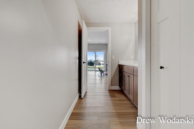 hallway with baseboards and light wood-style floors