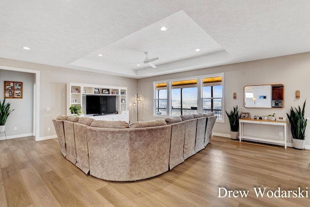 living area with light wood finished floors, baseboards, and a tray ceiling