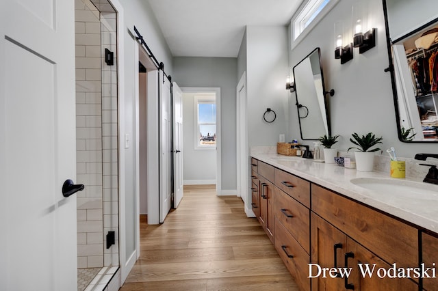 bathroom with double vanity, wood finished floors, a stall shower, and a sink