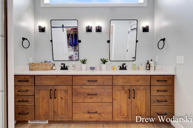 full bath featuring wood finished floors, a sink, and double vanity