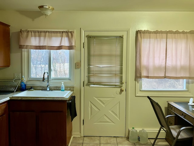 kitchen with a baseboard heating unit, light countertops, light tile patterned floors, and a sink