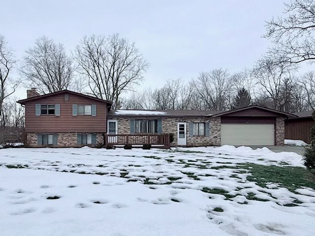 tri-level home featuring an attached garage, a chimney, and a deck