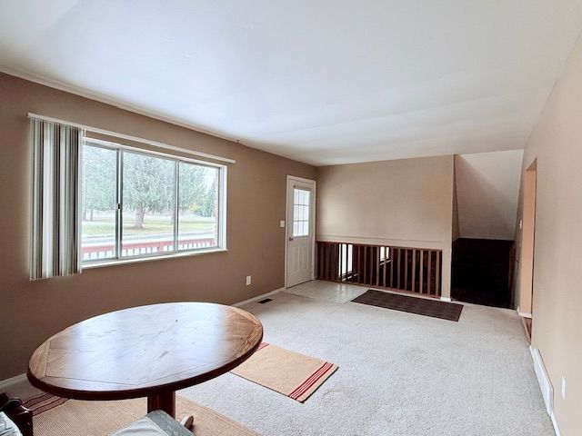 living room featuring baseboards, visible vents, and light colored carpet