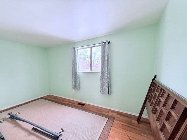 spare room with wood finished floors, visible vents, and baseboards