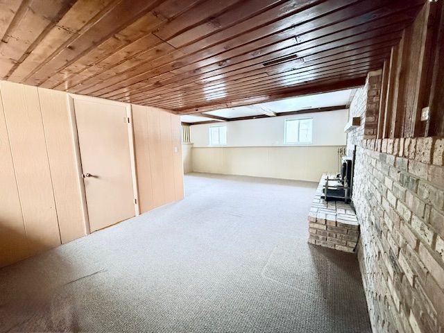 8530 Catherwood Dr, Goodrich, MI 48438 - basement featuring a wood stove, wooden ceiling, and carpet