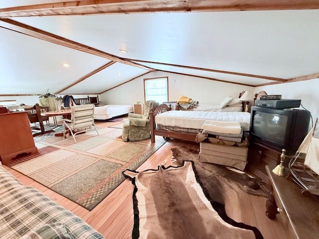 bedroom featuring lofted ceiling with beams and wood finished floors