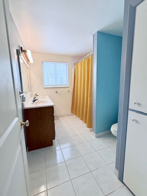 full bath with tile patterned flooring, toilet, a shower with shower curtain, vanity, and baseboards