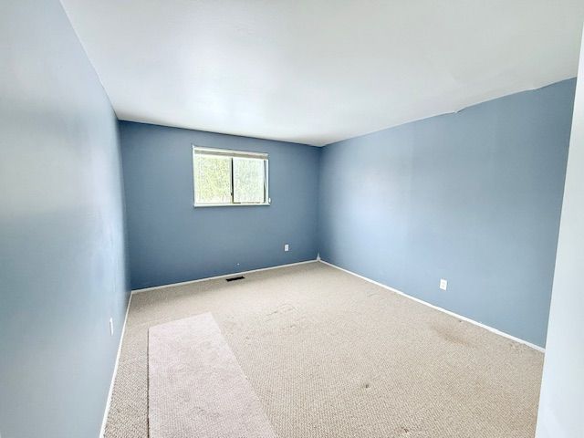 carpeted empty room with visible vents