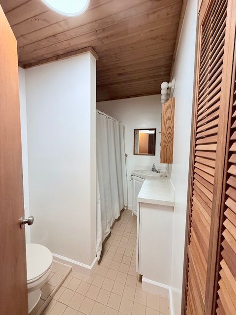 bathroom with toilet, wood ceiling, vanity, tile patterned flooring, and baseboards