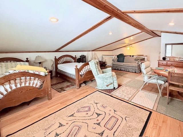 bedroom with lofted ceiling with beams and wood finished floors