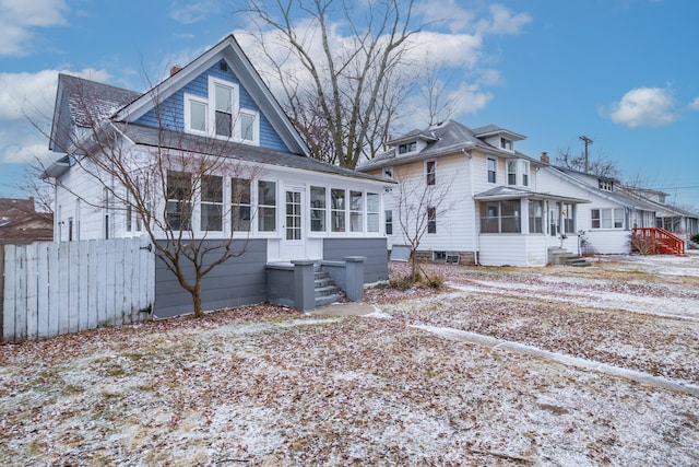 rear view of property featuring entry steps, fence, a sunroom, and a shingled roof