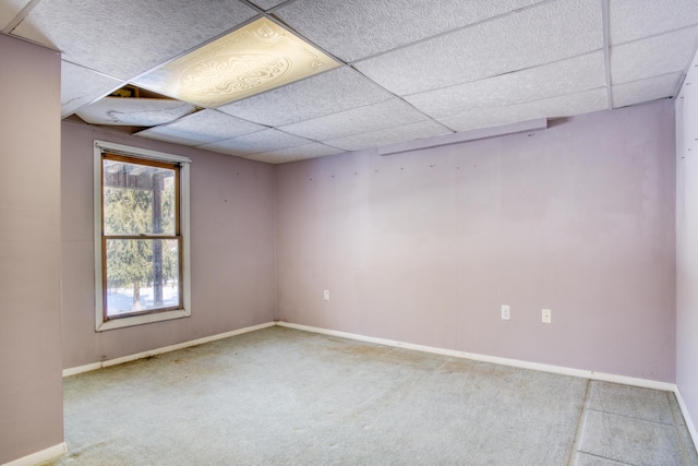 carpeted empty room with a drop ceiling and baseboards