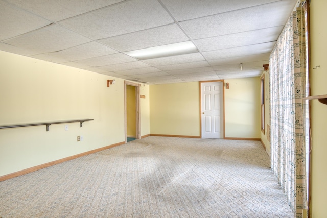 unfurnished room with light carpet, a drop ceiling, and baseboards