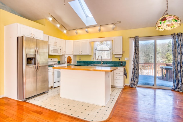 kitchen featuring white appliances, white cabinetry, a sink, and a center island