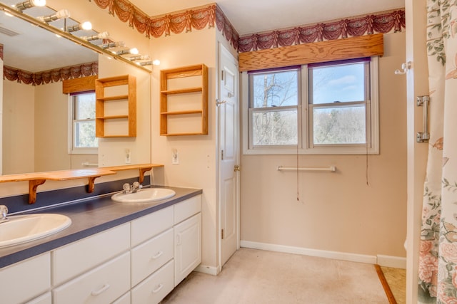 full bath with double vanity, a sink, visible vents, and baseboards