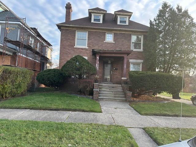 traditional style home with brick siding, a chimney, and a front yard