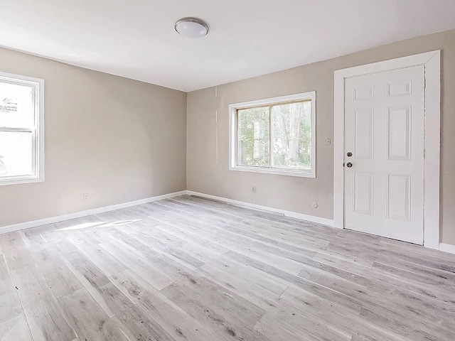 unfurnished room with baseboards and light wood-style floors