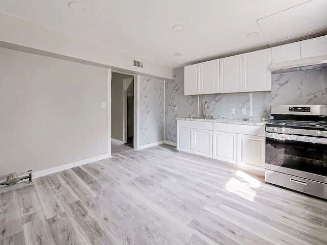 kitchen with stainless steel gas stove, visible vents, light wood finished floors, and white cabinetry