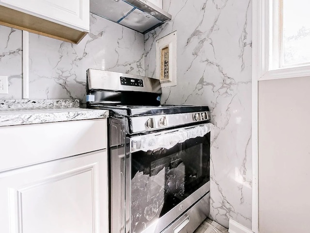 kitchen featuring under cabinet range hood, electric range, and white cabinets