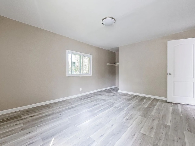 spare room featuring light wood finished floors and baseboards