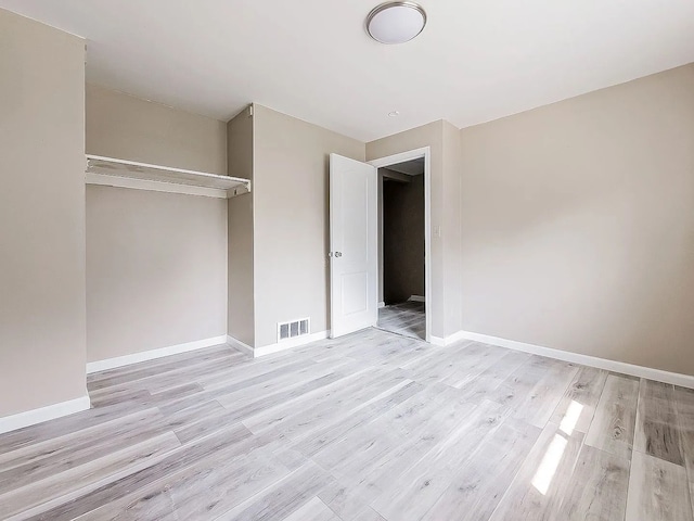 unfurnished bedroom featuring visible vents, wood finished floors, baseboards, and a closet