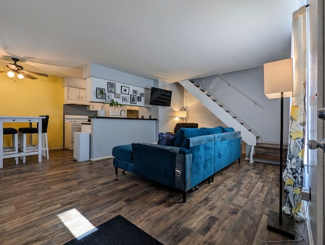 living area featuring a ceiling fan, dark wood-style flooring, and stairway