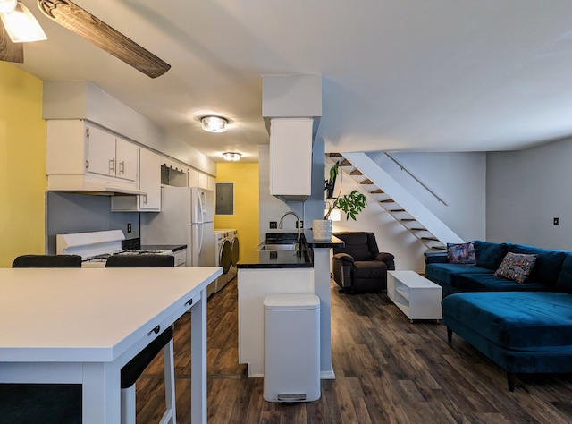 kitchen with range with gas cooktop, open floor plan, white cabinets, a sink, and a peninsula