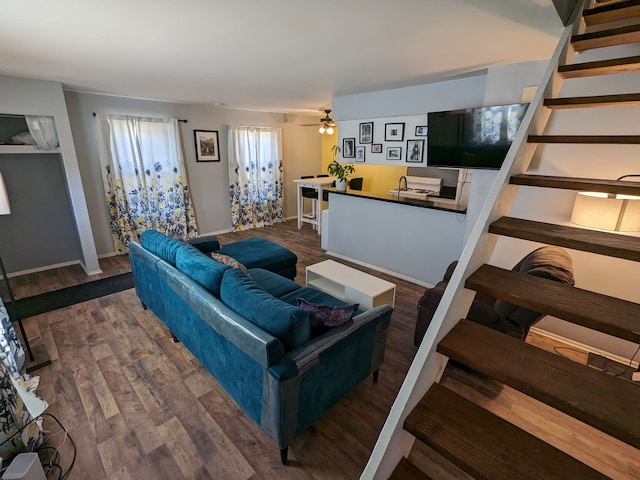 living room with stairway, wood finished floors, a ceiling fan, and baseboards