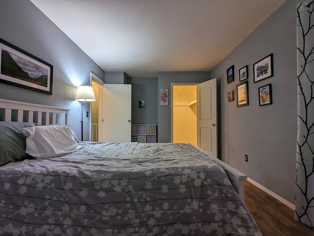 bedroom with dark wood-type flooring and baseboards