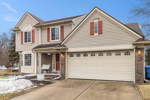 traditional-style home featuring covered porch, driveway, brick siding, and a garage