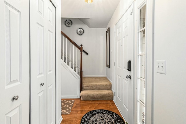 foyer featuring dark wood-type flooring, stairway, and baseboards