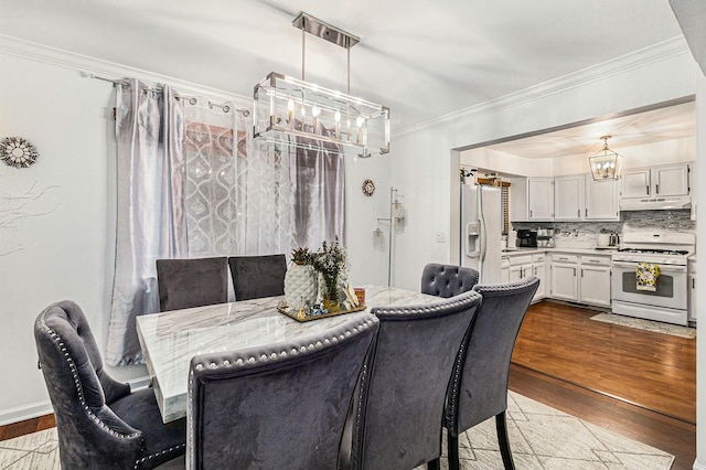 dining area featuring ornamental molding, a notable chandelier, baseboards, and wood finished floors