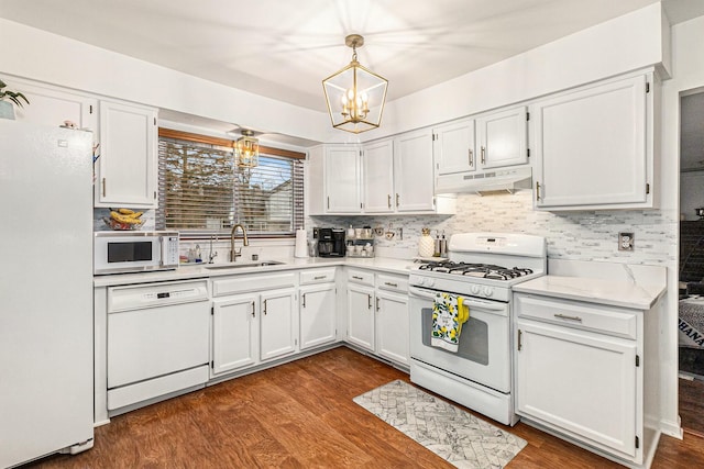 kitchen with dark wood-style floors, white appliances, a sink, and under cabinet range hood