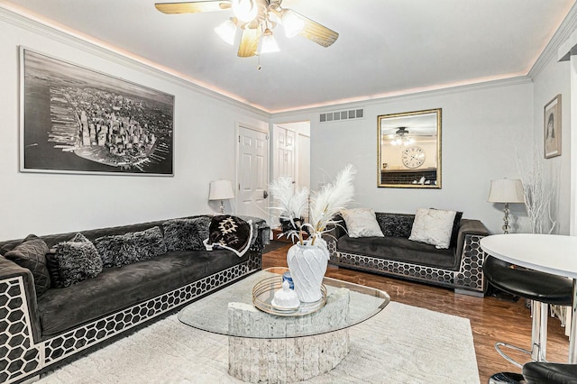 living room featuring ornamental molding, visible vents, ceiling fan, and wood finished floors