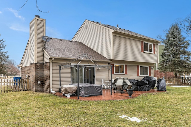 back of property with a chimney, fence, a yard, a patio area, and brick siding