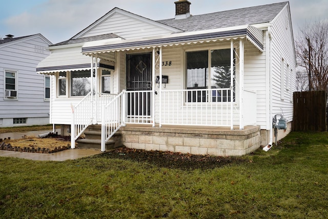 bungalow with covered porch, a shingled roof, a chimney, and a front yard