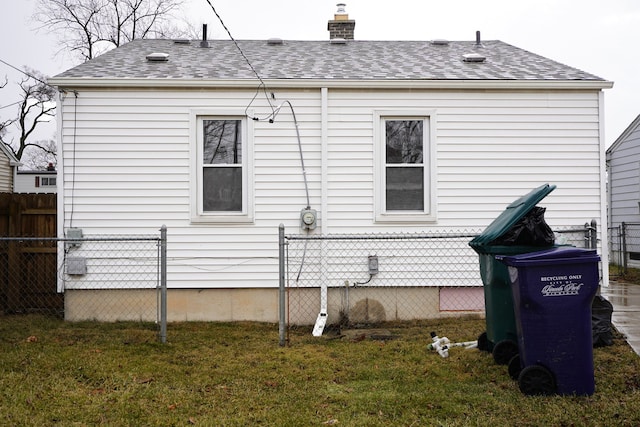 view of home's exterior with a yard, fence, a chimney, and a shingled roof