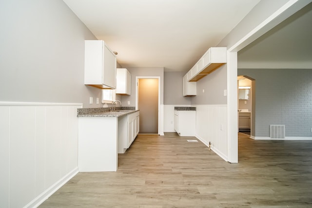 kitchen with light wood-style floors, visible vents, a sink, and white cabinetry