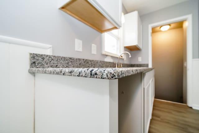 kitchen featuring light countertops, wood finished floors, a sink, and white cabinets