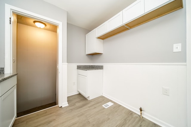 clothes washing area with light wood-type flooring and visible vents